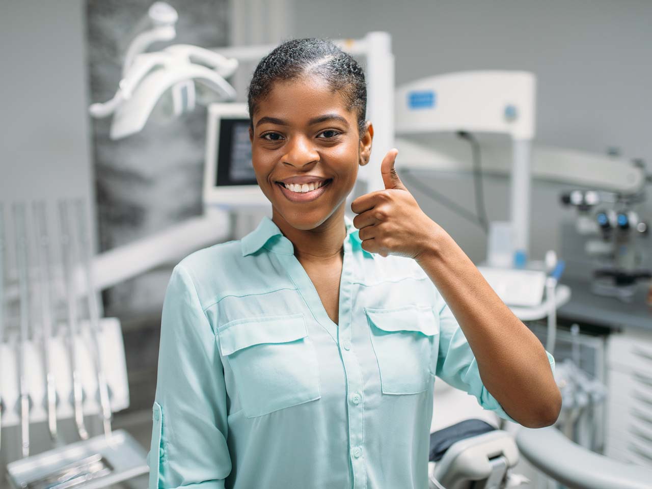 Smiling woman giving thumbs up in dental exam room