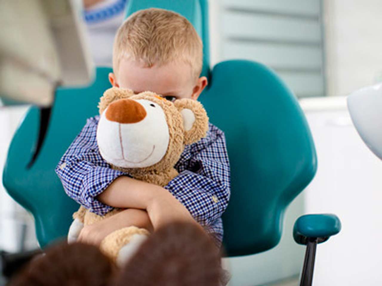 toddler boy holding stuffed animal in dentist chair