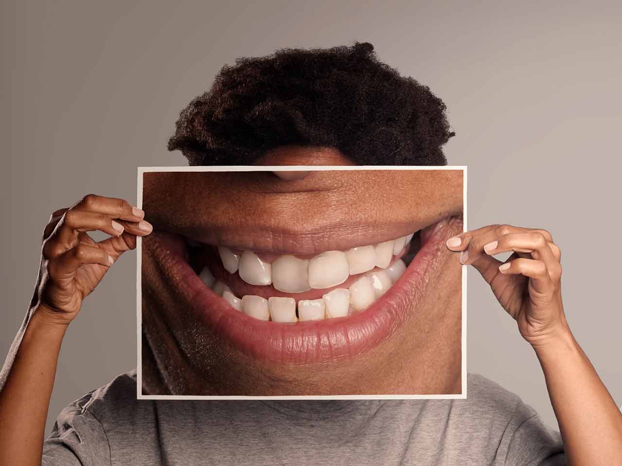 boy holding large image of smiling mouth over his face