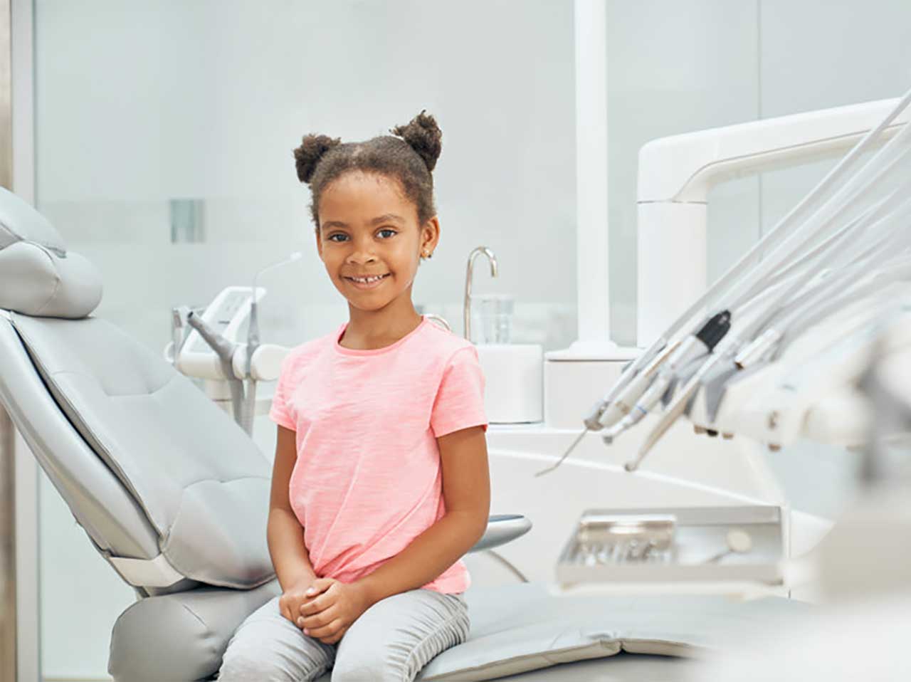 girl in pink t-shirt sitting on dental chair in bright office