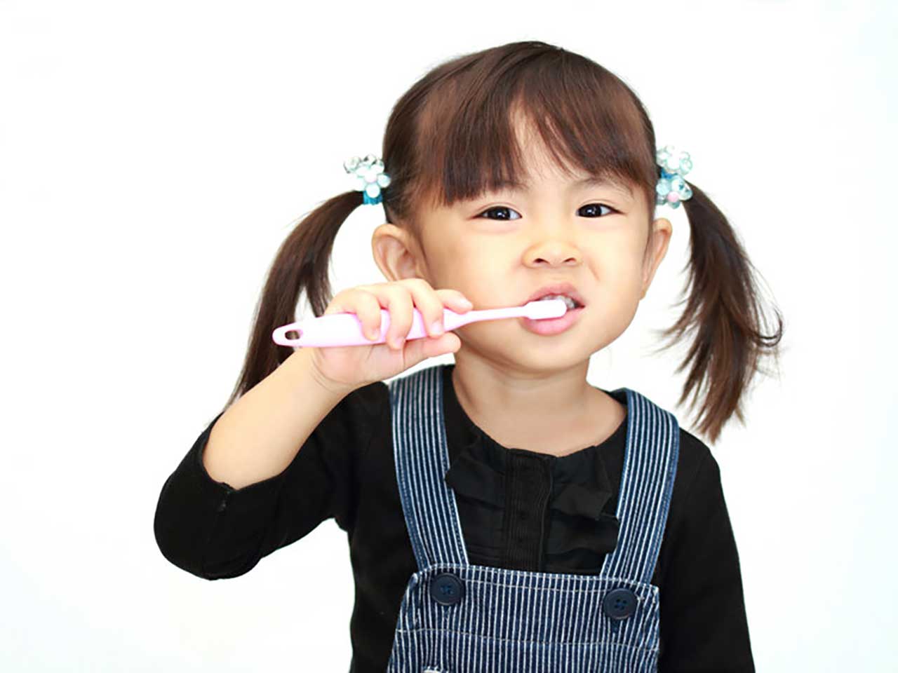 young girl with pigtails brushing her teeth