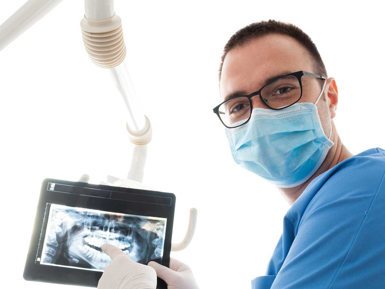 man in surgical mask and scrubs holding dental x-ray