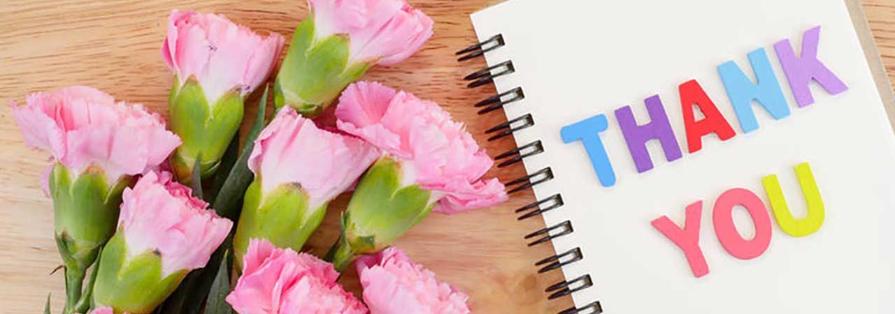 Flowers and notebook with "thank you" message