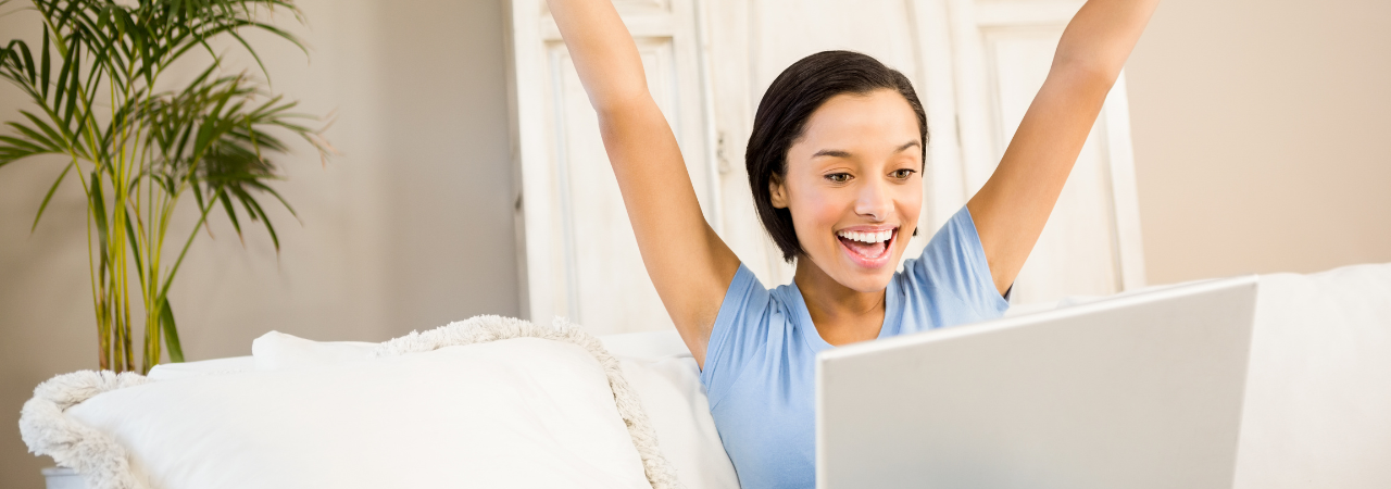 woman using her laptop and raising her hands in celebration