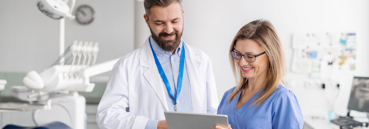 dental assistant looking at a tablet while talking to dentist