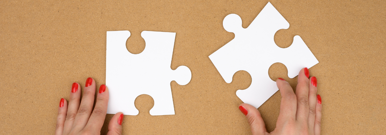 2 hands putting two large white puzzle pieces together