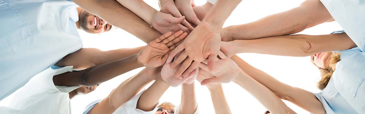 a team of dental professionals puts their hands together in a huddle