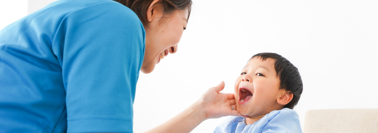 Woman with her hand on the cheek of a child smiling with his mouth open