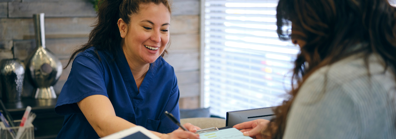 a dental office manager helps a patient fill out a form