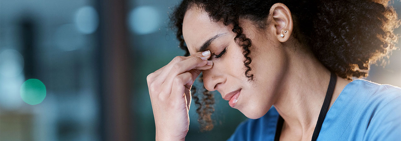 dental assistant looking stressed and holding the bridge of their nose between their fingers