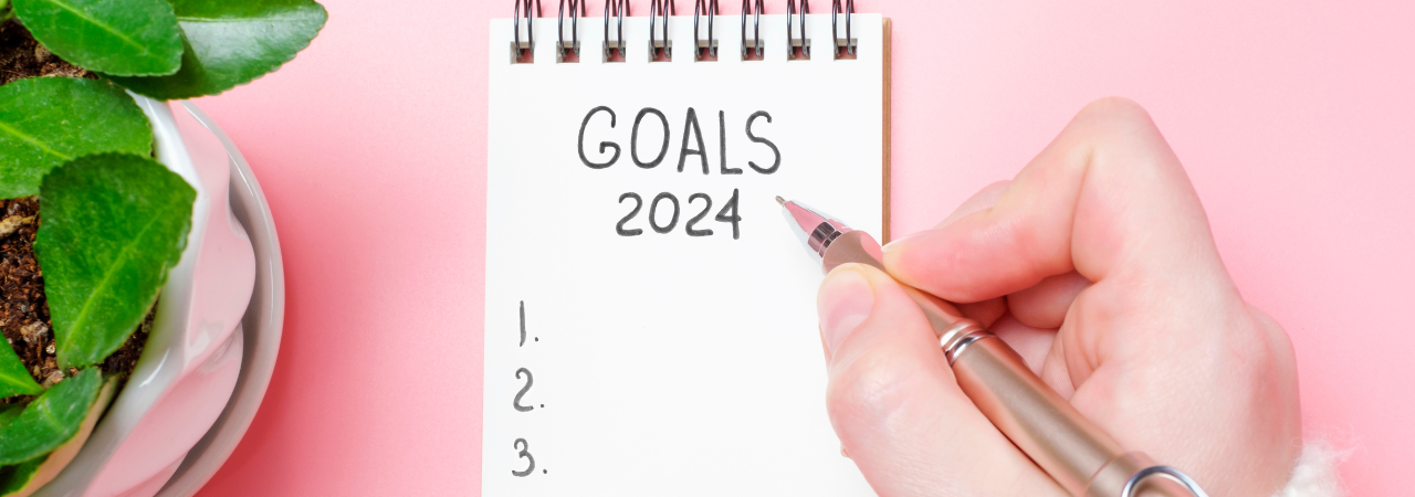 person writing their 2024 goals in a notebook