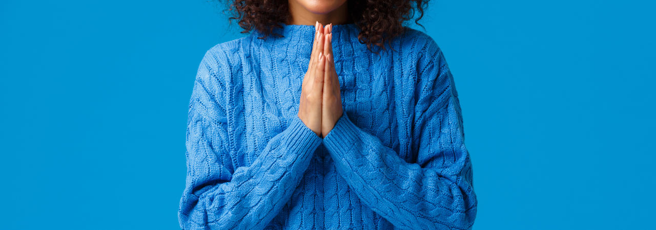 woman with hands pressed together in a wishful or praying manner