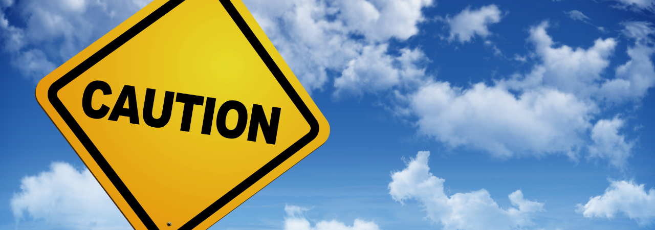 Yellow caution sign against a blue-sky background.