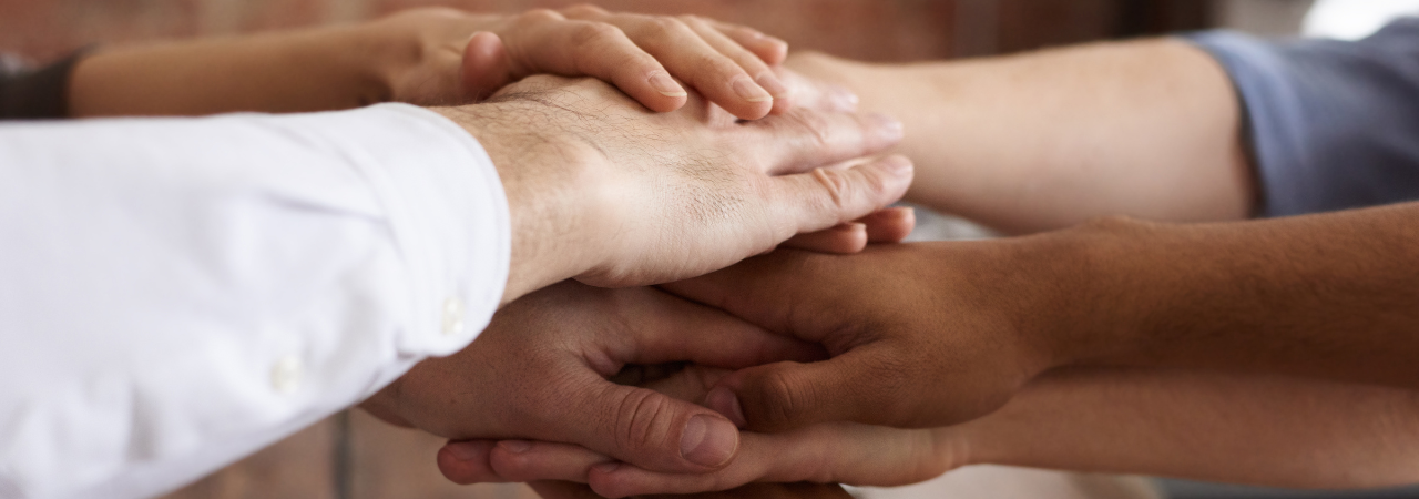 team members place their hands on top of each other