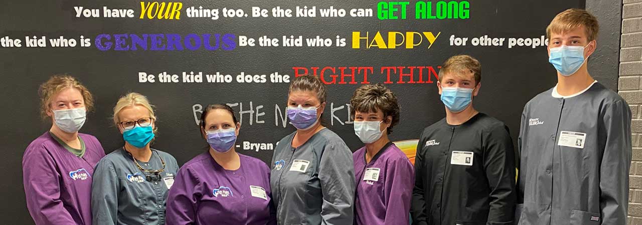 Group of dental assisting students wearing masks in front of chalkboard