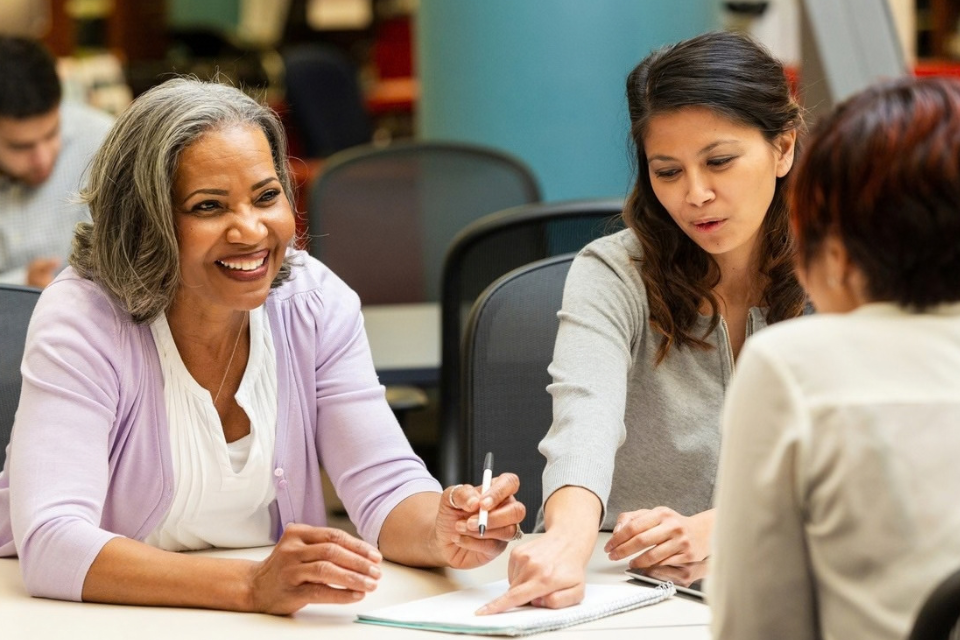 Diverse group of women in an indoor setting actively collaborating and engaged in conversation during a class or meeting
