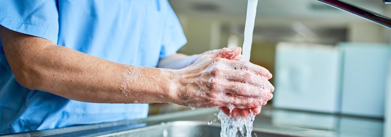 person wearing scrubs washing their hands