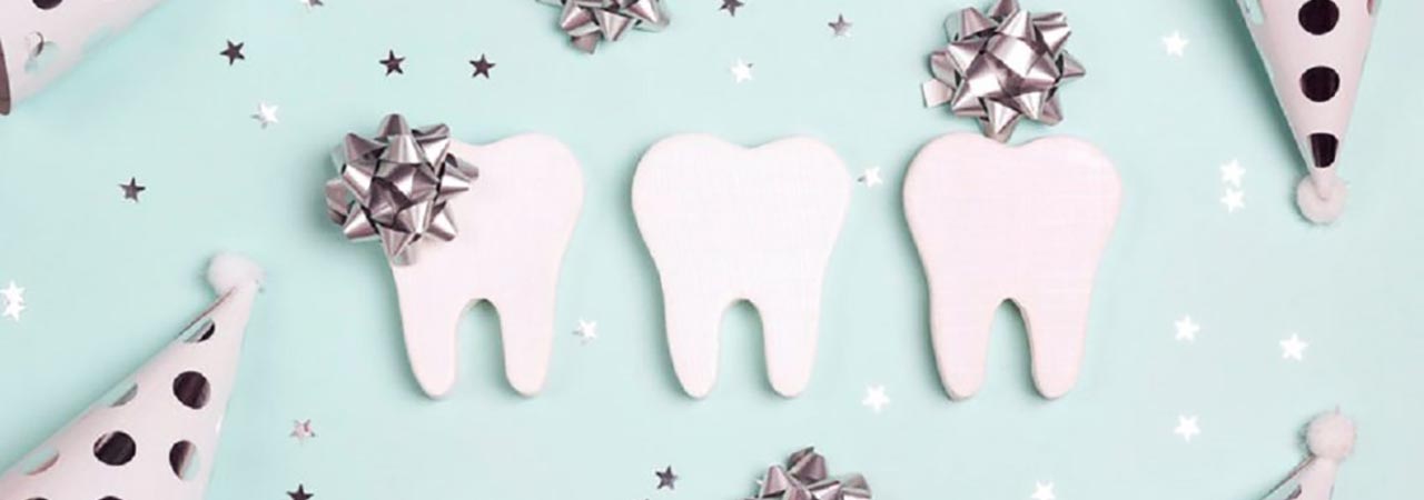 tooth shape cutouts with party hats and silver stars on blue background