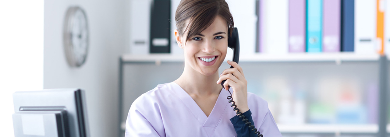 Dental assistant in scrubs in dental office talking on phone