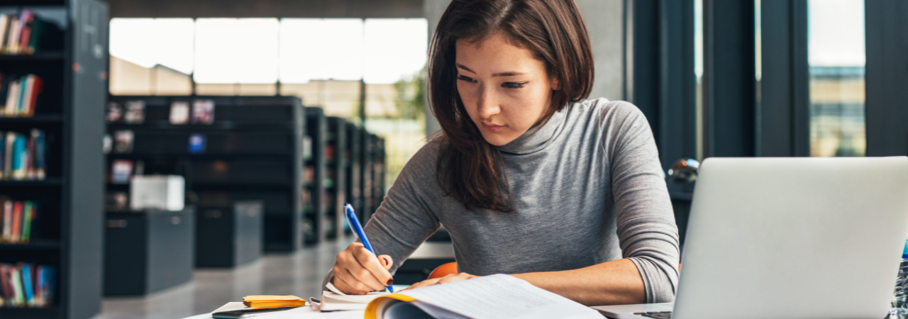 woman studying and taking notes in a library