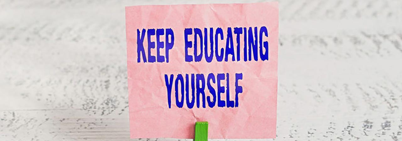 "keep educating yourself" message on pink paper with white wood background