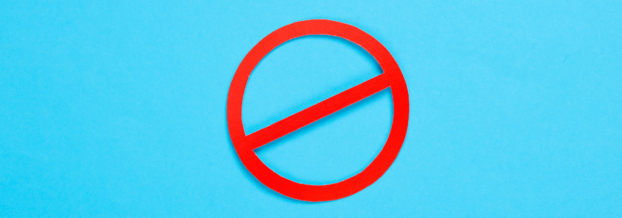 A red circle with a diagonal line through it against a bright blue background