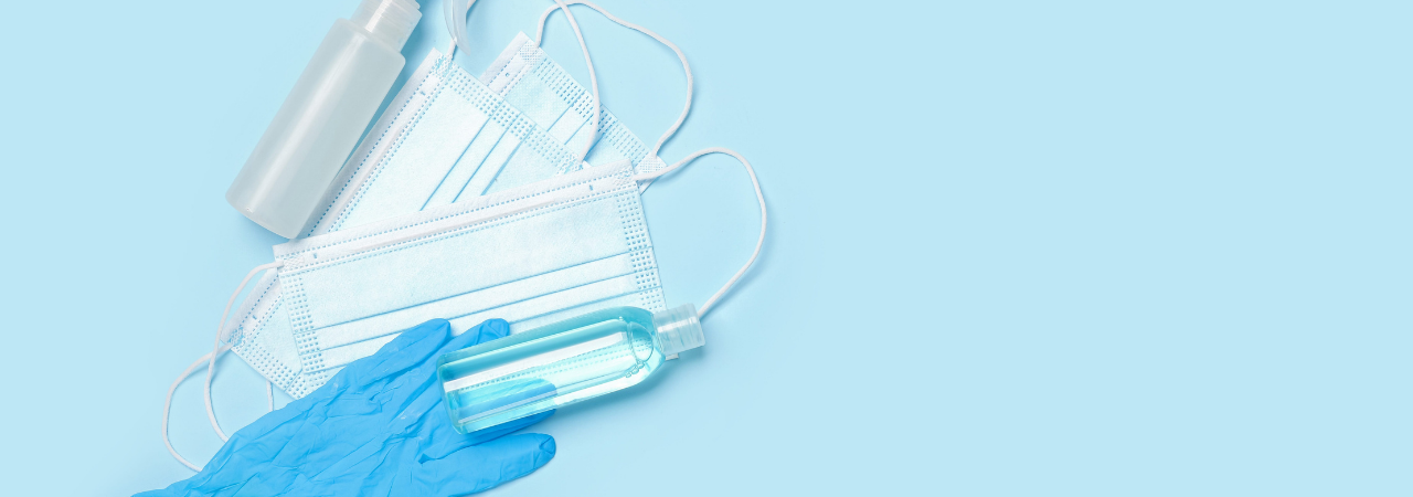 A spray bottle, masks, and gloves laid on a blue background