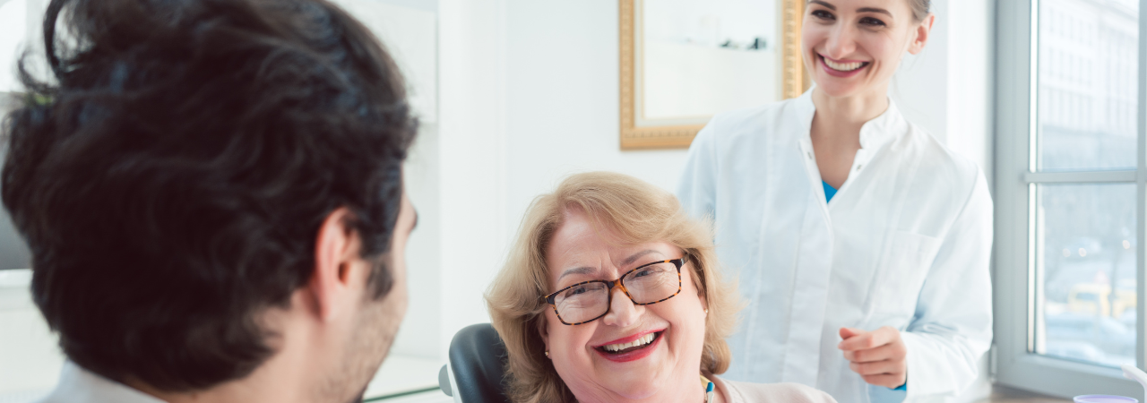 patient talks with dentist and dental assistant