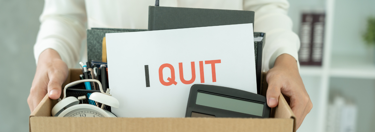 A box full of office equipment and a sign that says, "I Quit".