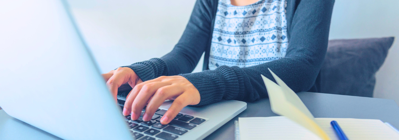 woman using laptop with notebook