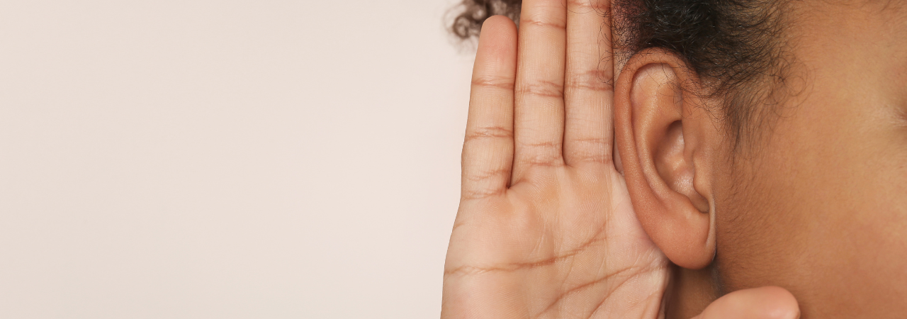 woman holding hand up to ear to listen