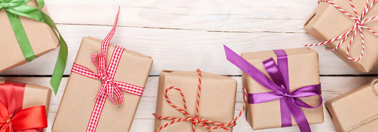 gifts wrapped in brown paper and colorful ribbons on wood backdrop