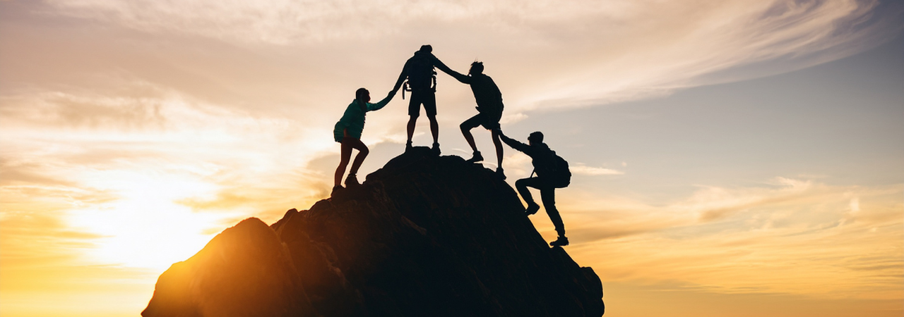 silhouette of people climbing a mountain