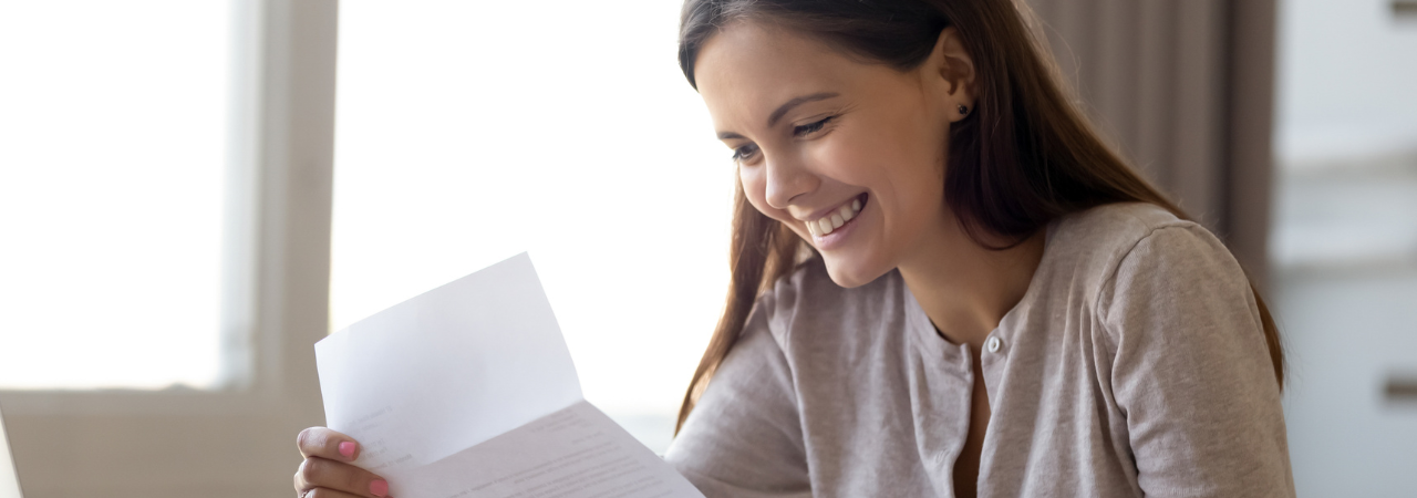 woman smiling while reading a letter