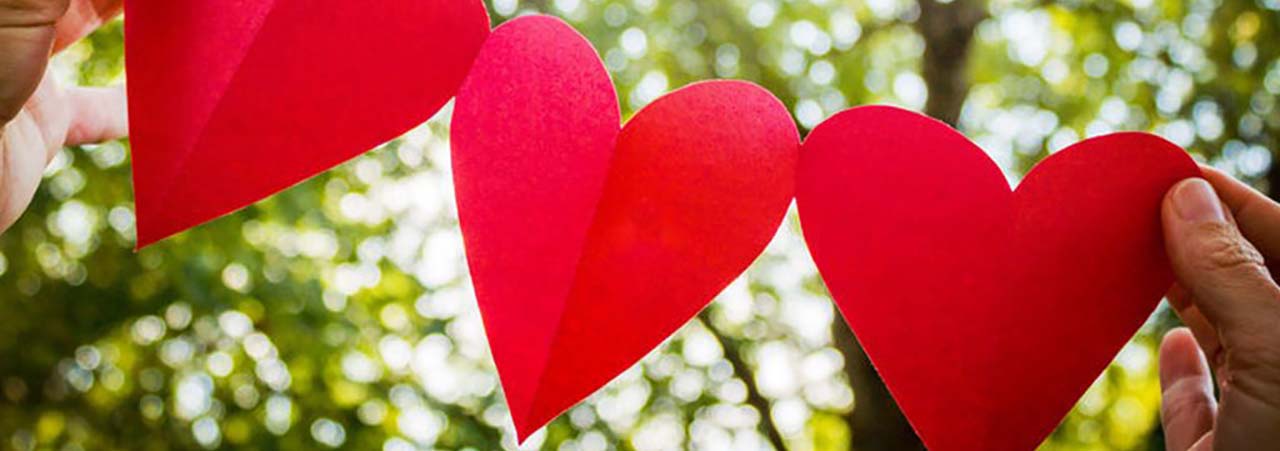 hands holding cut out strand of paper hearts