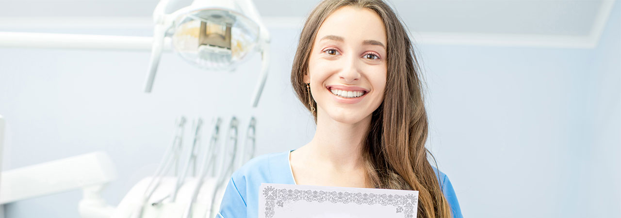 female dental assistant holding certificate in dental treatment room