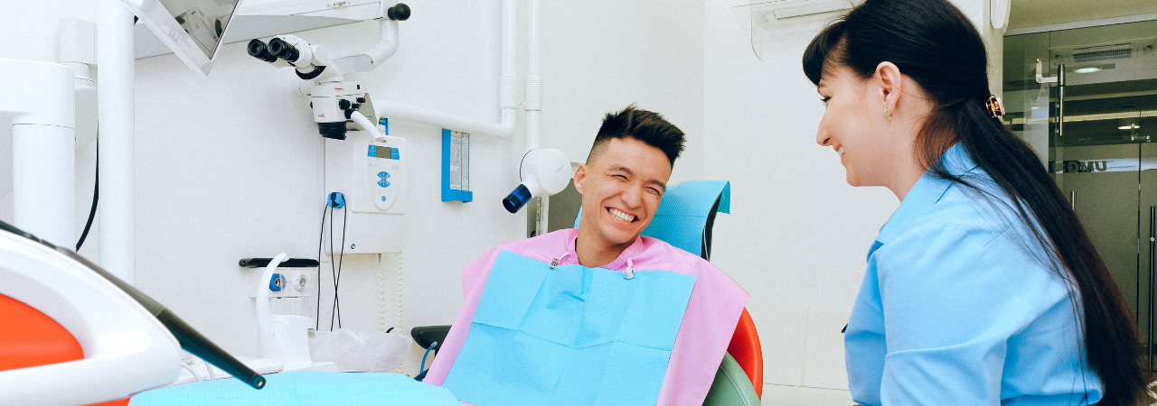 smiling dental assistant talks to happy patient