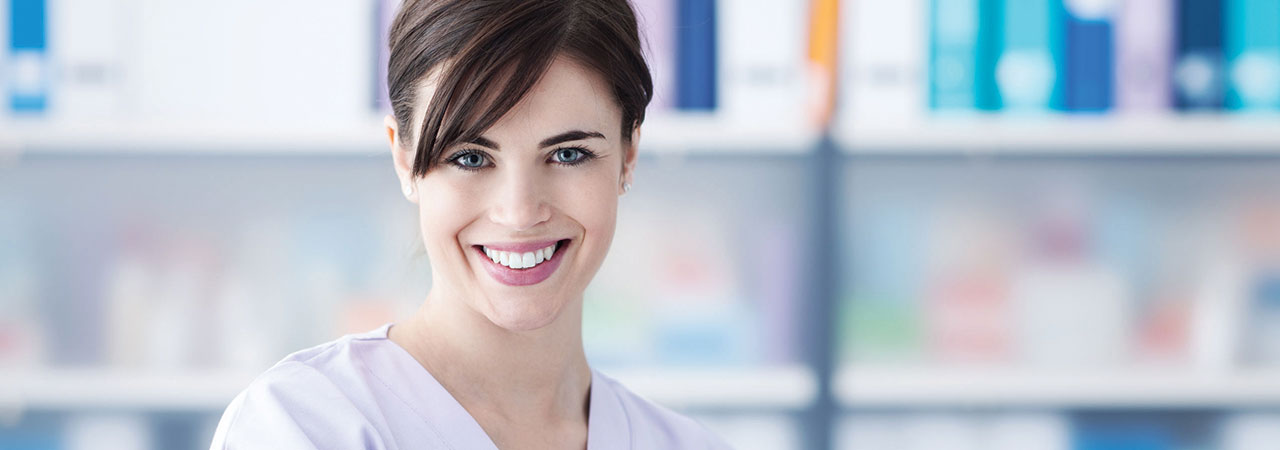 Smiling dental assistant in front of shelf with supplies