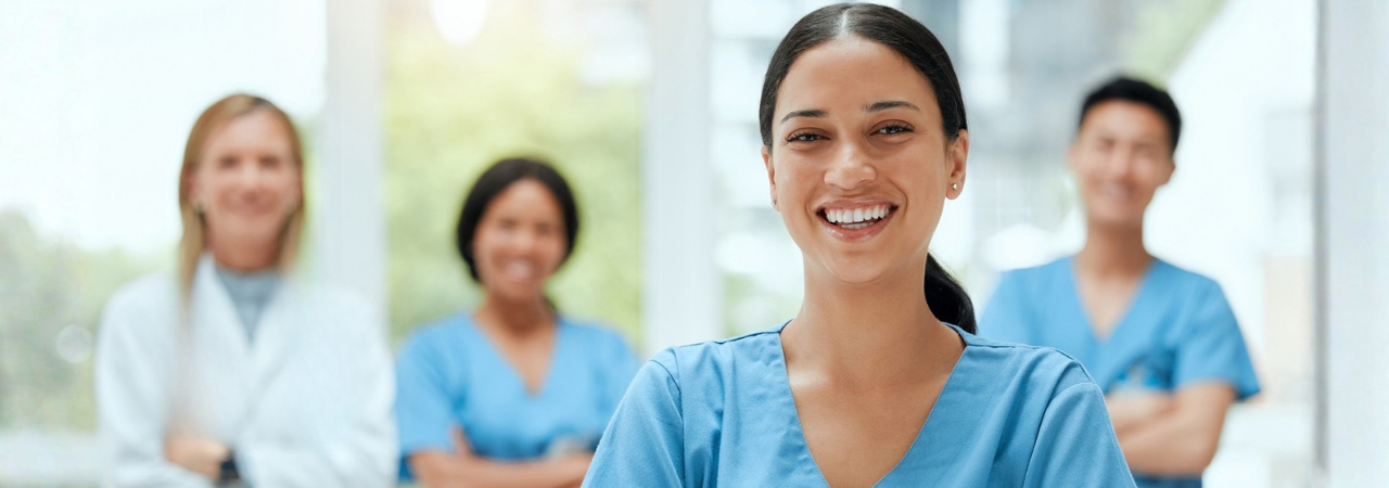 smiling dental assistant with team in background