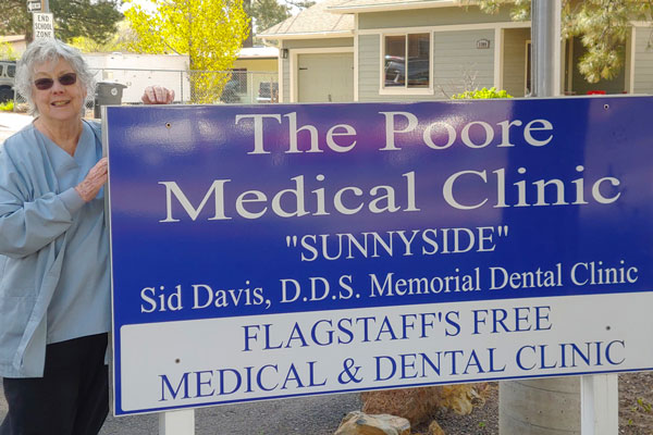 Maureen Pisano posing next to Sid Davis Memorial Dental Clinic sign