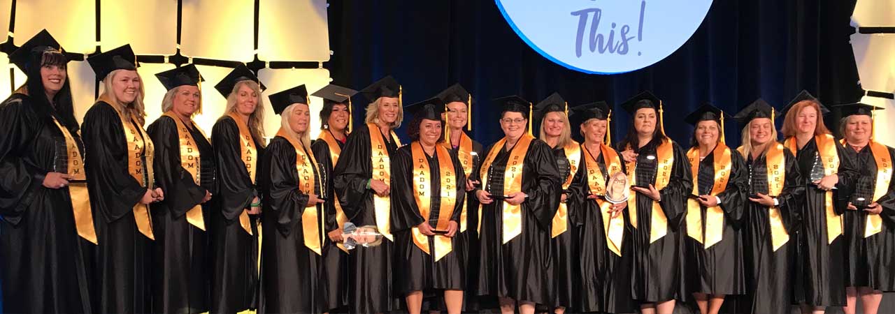 Members from the first-ever class of DAADOMs on stage wearing caps and gowns