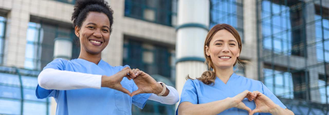 two dental assistants smiling and making heart hands